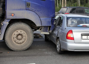 Aftermath of a trucking accident between a truck and a small sedan, where comparative fault laws may help determine compensation.