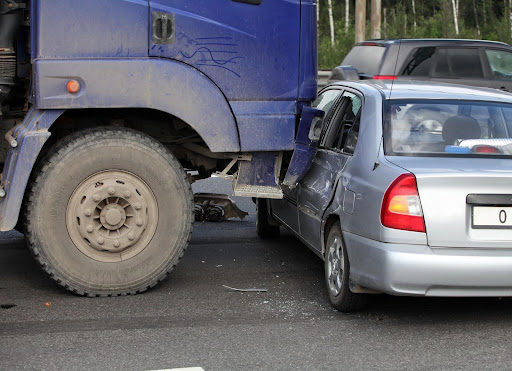 Aftermath of a trucking accident between a truck and a small sedan, where comparative fault laws may help determine compensation.